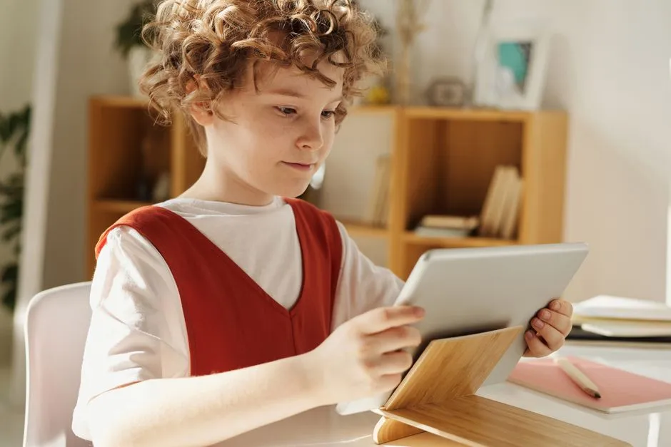 Child holding a tablet, browsing an educational activity during a distance-learning session